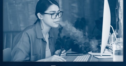 Frau vapt am Arbeitsplatz vor dem PC
