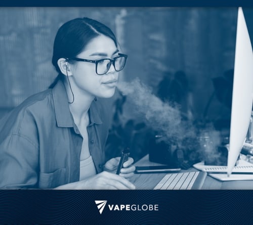 Frau vapt am Arbeitsplatz vor dem PC