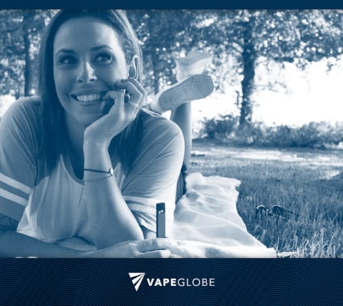 Beim Vaping in der Öffentlichkeit liegt eine Frau auf einer Decke im Park. 