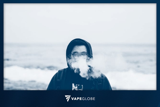 Ein Mann in Kapuzenpullover dampft am Meer,  als Titelbild für den Artikel über häufige Anfängerfehler beim Vapen. 