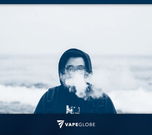 Ein Mann in Kapuzenpullover dampft am Meer,  als Titelbild für den Artikel über häufige Anfängerfehler beim Vapen. 