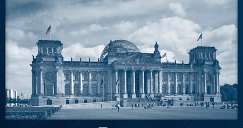 Der deutsche Bundestag mit Menschen auf der Wiese davor. 